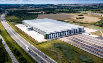 Arial photograph of a really large commercial wharehouse beside a motorway